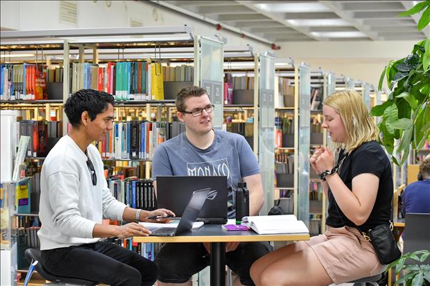 Tre studenter som jobber sammen på biblioteket
