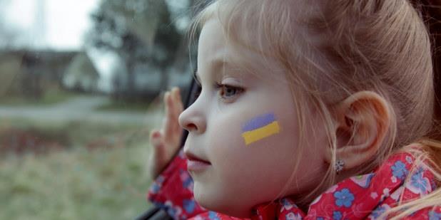 Liten jente med ukrainsk flagg tegnet på kinnet. Foto.
