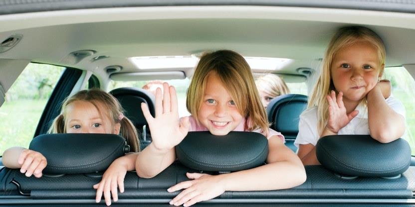 Tre barn i baksetet på en bil. Foto.