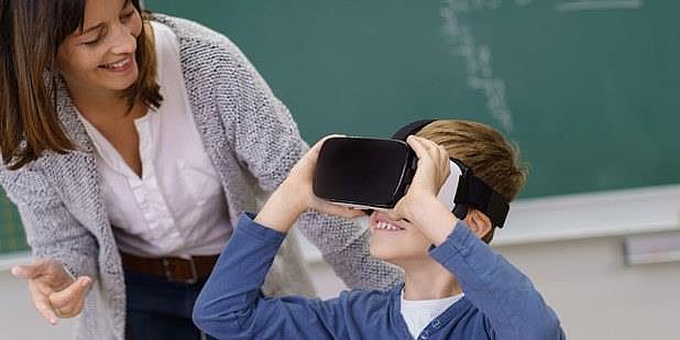 Foto av kvinnelig lærer sammen med elev som bruker VR-briller. 