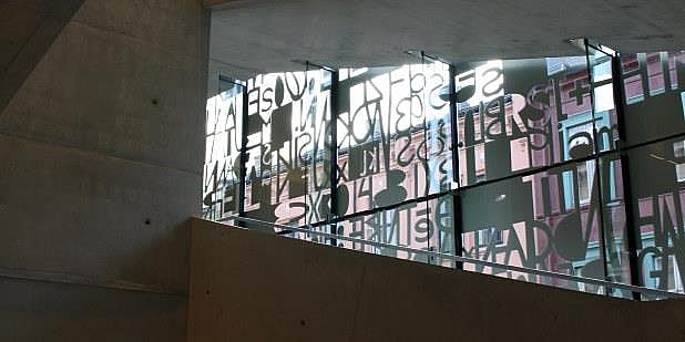 Glassvegg med bokstaver i lærernes hus. Foto.