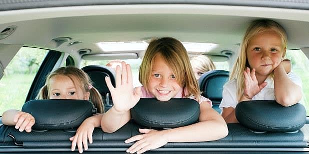 Tre barn i baksetert på en bil. Foto