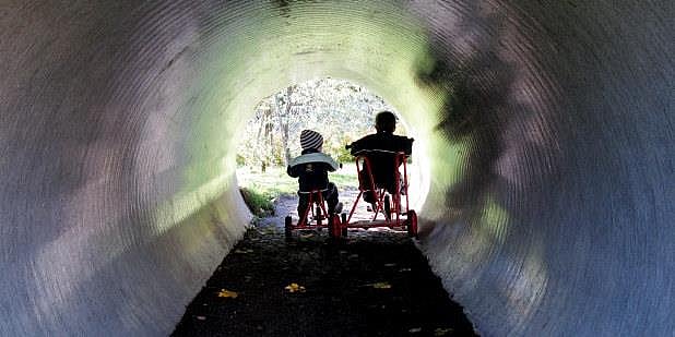 To barnehagebarn som sitter på en sykkel - inne i en tunnel. Illustrasjonsfoto.