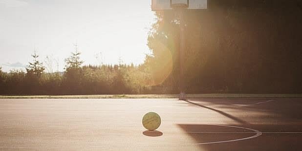 En ball som ligger på en bakken på en utendørs basketbane. Foto.