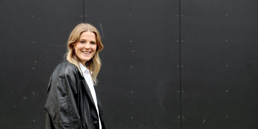 Bilde av en smilende Birgitte Fjørtoft. Hun er vendt mot kameraet, med svart bakgrunn.