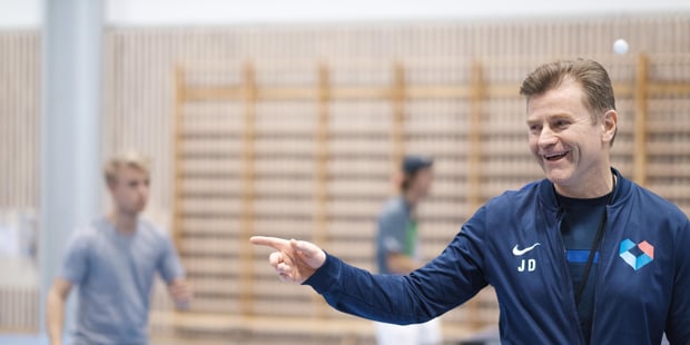 Mannlig kroppsøvingslærer som instruerer en gutt som spiller bordtennis i en gymsal.