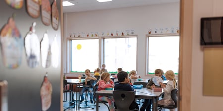 Bildet viser elever ved Oksenøya barneskole, 1. og 6. klasse i 2024. Disse små barna sitter i klasserommet og spiser nistepakken sin.
