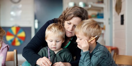 Kvinnelig barnehagelærer sitter med to barn ved bordet
og leker med naturgummi. Inne