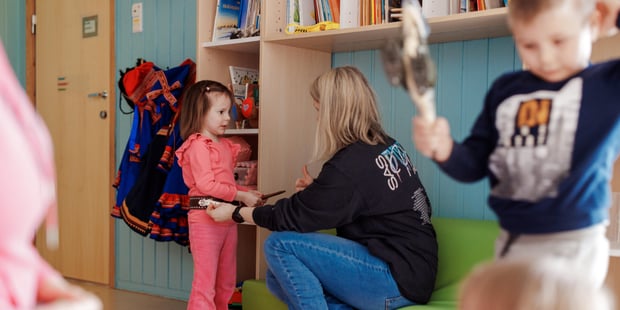Samisk barnehage, Inne, Barn og kvinnelig barnehagelærer er sammen, Barnehagelæreren sitter og snakker med et av barna.