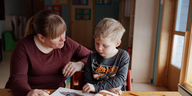 Samisk barnehage, Barn og barnehagelærer sitter ved bordet inne og leser i bøker