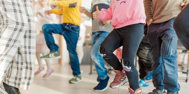 Bildet viser elever ved en barneskole som beveger seg i klasserommet, det ser ut som høye kneløft. Vi sr bare elevene fra livet og ned.