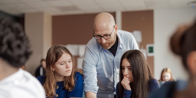 Videregående skole, Mannlig lærer veileder elever i klasserommet.