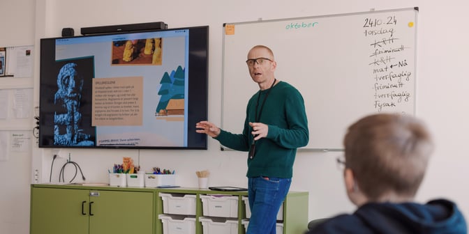 Foto av mannlig lærer som står foran tavle og underviser