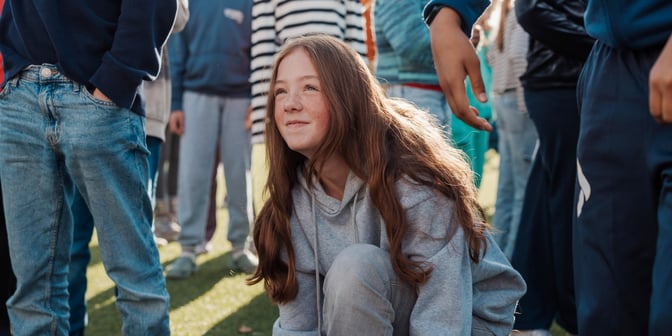 Bildet viser en elev ved Oksenøya barneskole. Hun ser ut til å knyte skoen, mens hun titter opp.