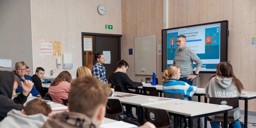 Klasserom med flere elever og 3 lærere, En lærer står foran tavle og sier noe. Foto