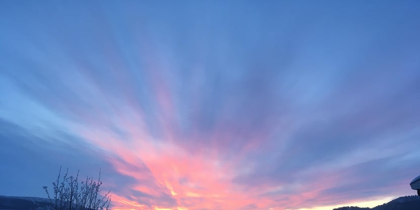 Rosa himmel over elva Karasjohka. I forgrunnen en garasje, og i bakgrunnen hvite trær og hvite hustak.