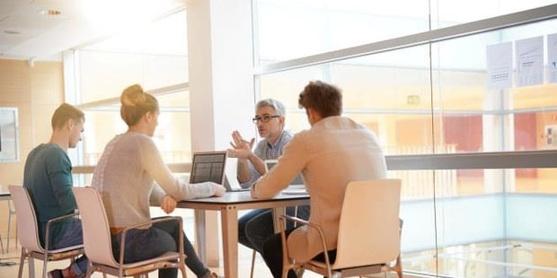 Fire personer som sitter rundt et bord og diskuterer