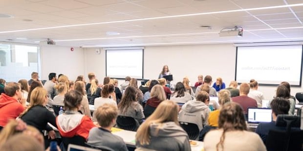 En sal full av mennesker som lytter til en som står foran og taler