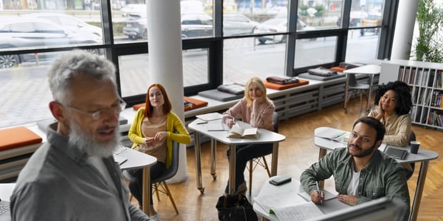 Foto av lærer med voksne elever i bakgrunnen