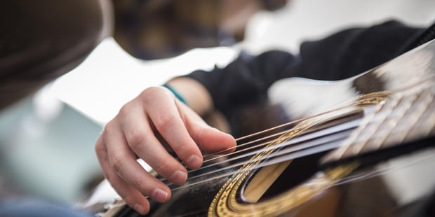 Illustrasjonsbilde av hånd som spiller på gitarstrenger
