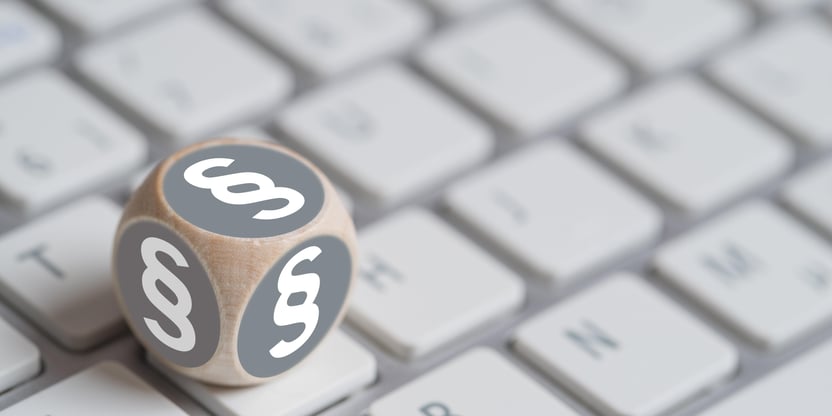 Terning med paragraftegn på alle sider, liggende oppå et tastatur