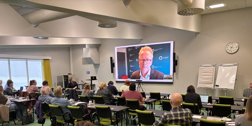 Bilde fra kurssal under hovedtillitsvalgt og lokallagsledersamling i Alta. PÅ storskjerm vises leder i Utdanningsforbundet, Geir Røsvoll. I salen sitter mange tilhørere.