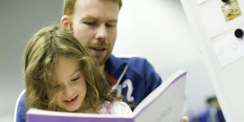 En lærer leser i en bok sammen med et barn. Illustrasjonsfoto. 
