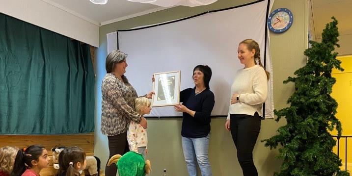 Fylkesleder overrekker klimapris til styrer i Nesset barnehage foran barna i barnehagen. 