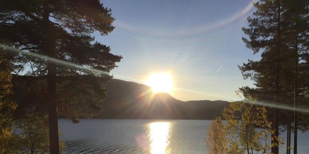 Soloppgang ved en innsjø. Foto.