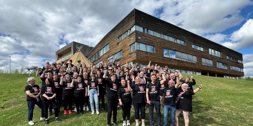 Bildet viser en større gruppe mennesker, stående på en grønn gressbakke i forkant av Samisk høgskole i kautokeino. Det står også en beige lavvu der. Alle har på seg Unio i streik skjorter. De fleste med samisk trykk (Unio - Bargoheaitta!) Nesten alle holder opp en knyttet neve i protest mot Statens ønske om å tvinge alle over på en tariffavtale. Foran i midten fylkesleder Sissel B. Henriksen.
