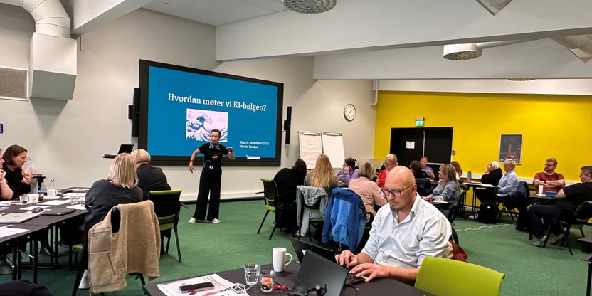 En svært engasjert Merete Henden foreleser for lokallagsledere og hovedtillitsvalgte på kurs. Henden står foran en skjem med tittelen "Hvordan møter vi KI-bølgen?" I lokalet sitter det mange tillitsvalgte som følger med.