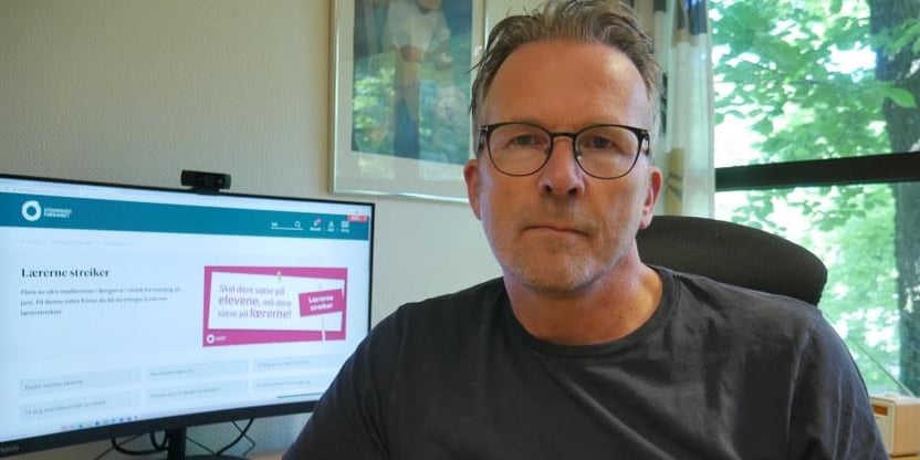 Geir Røsvoll, fylkesleder, sitter ved pulten på et kontor.  Foto.