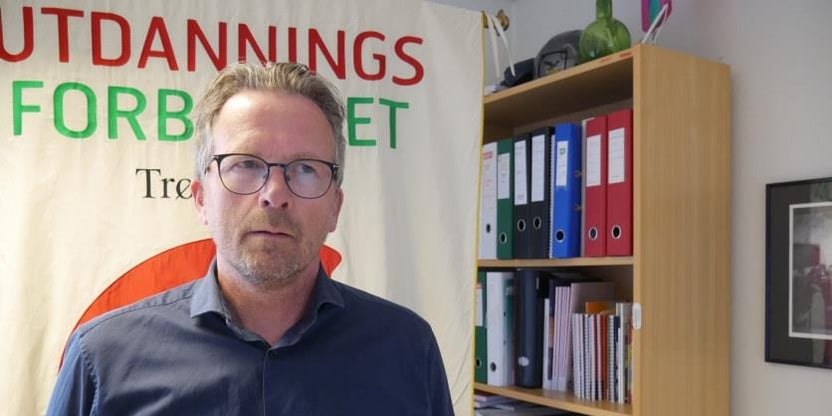 Fylkesleder i Trøndelag, Geir Røsvoll i et kontor, med Utdanningsforbundet Trøndelags fane bak seg. Foto.