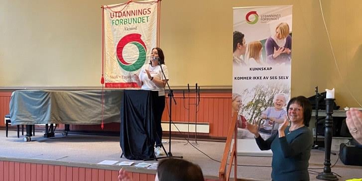 Streikeleiar Ina Enoksen står på podiet og gratulerer dei streikande i Ålesund. 