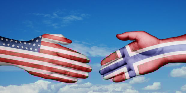Hender som strekker seg mot hverandre med amerikansk og norsk flagg på.
