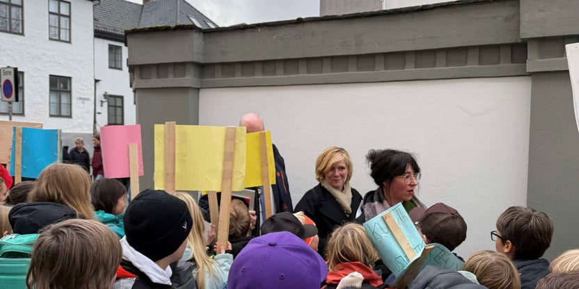 Bilde av demonstranter utenfor Bergen rådhus og Byrådsleder Christine Meyer på vei inn til møte