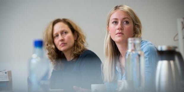 To personer som sitter rundt et bord og lytter. Foto. 