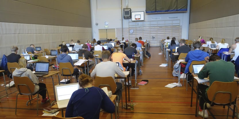 Bilde av elever som har skriftlig eksamen i en gymnastikksal