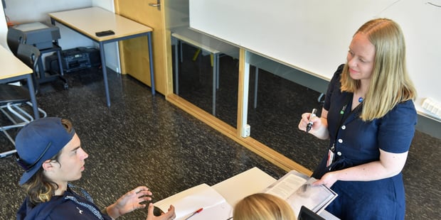 Kvinnelig lærer underviser to elever. Foto.