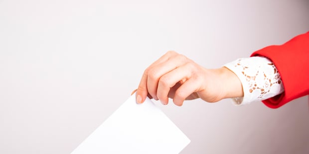 En person som legger en stemmeseddel i en boks