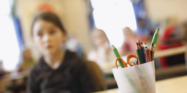 En jente sitter i et klasserom. Foto.