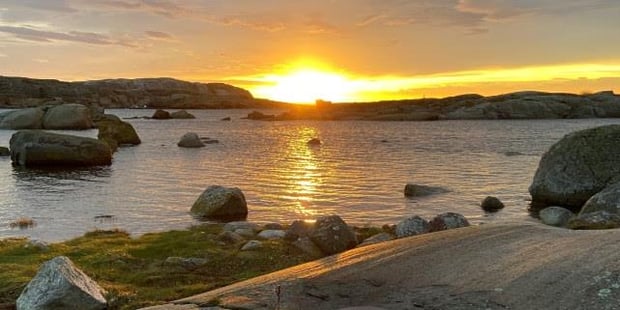 Soloppgang ved en fjord. Foto. 