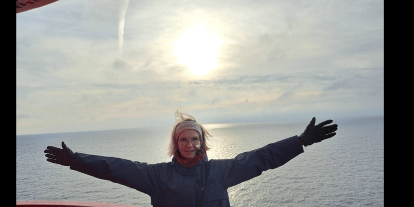 Kvinne avbildet i halvfigur med himmel og hav i bakgrunnen