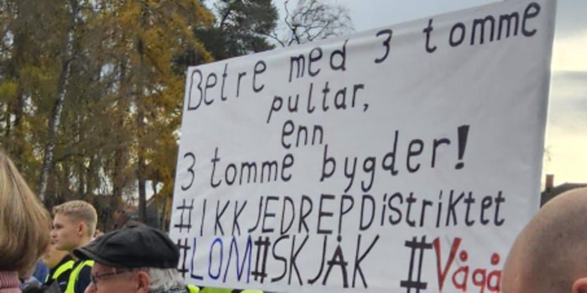 Bilde av plakat fra markeringen på Hamar med påskriften: Betre med 3 tomme pulter enn 3 tomme bygder