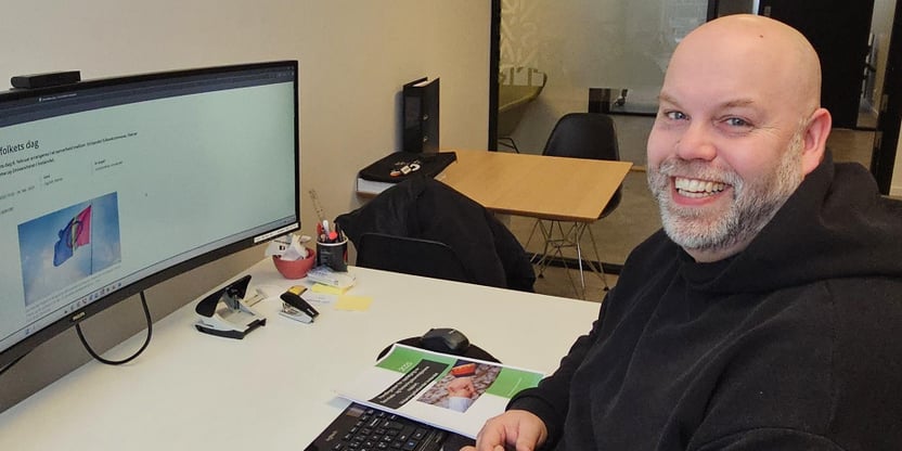 Bilde av Bjørn Martinsen sittende foran sin pc, med bilde av arrangement fra Universtitet i Innlandet på samenes nasjonsaldag