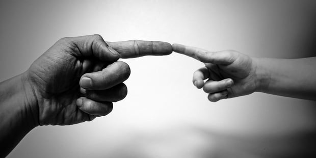 Bildet viser en voksen hand og en barnehand som peker på hverandre.