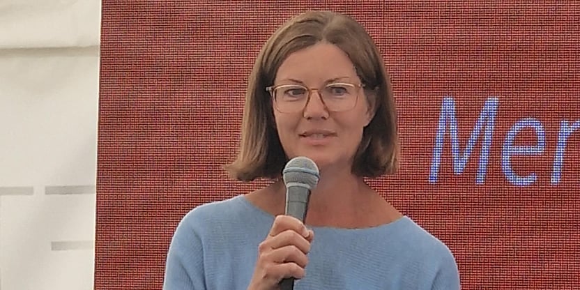 Dame som holder mikrofon. Avbildet i halvfigur