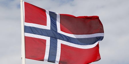 Bildet viser det norske flagget som blafrer i vinden.