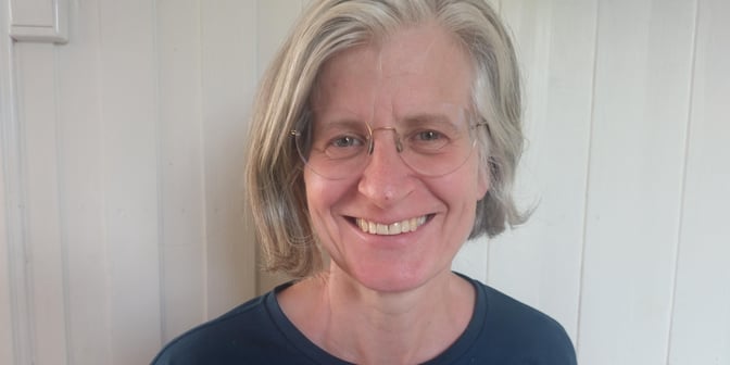 Nærbilde av Elin Tandberg, som smiler. Hun har briller og halvlangt hår.