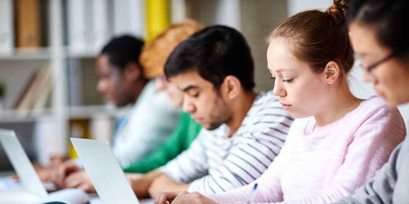 Bilde av fire studenter som en ser i profil, mens de jobber på pc/leser i bok